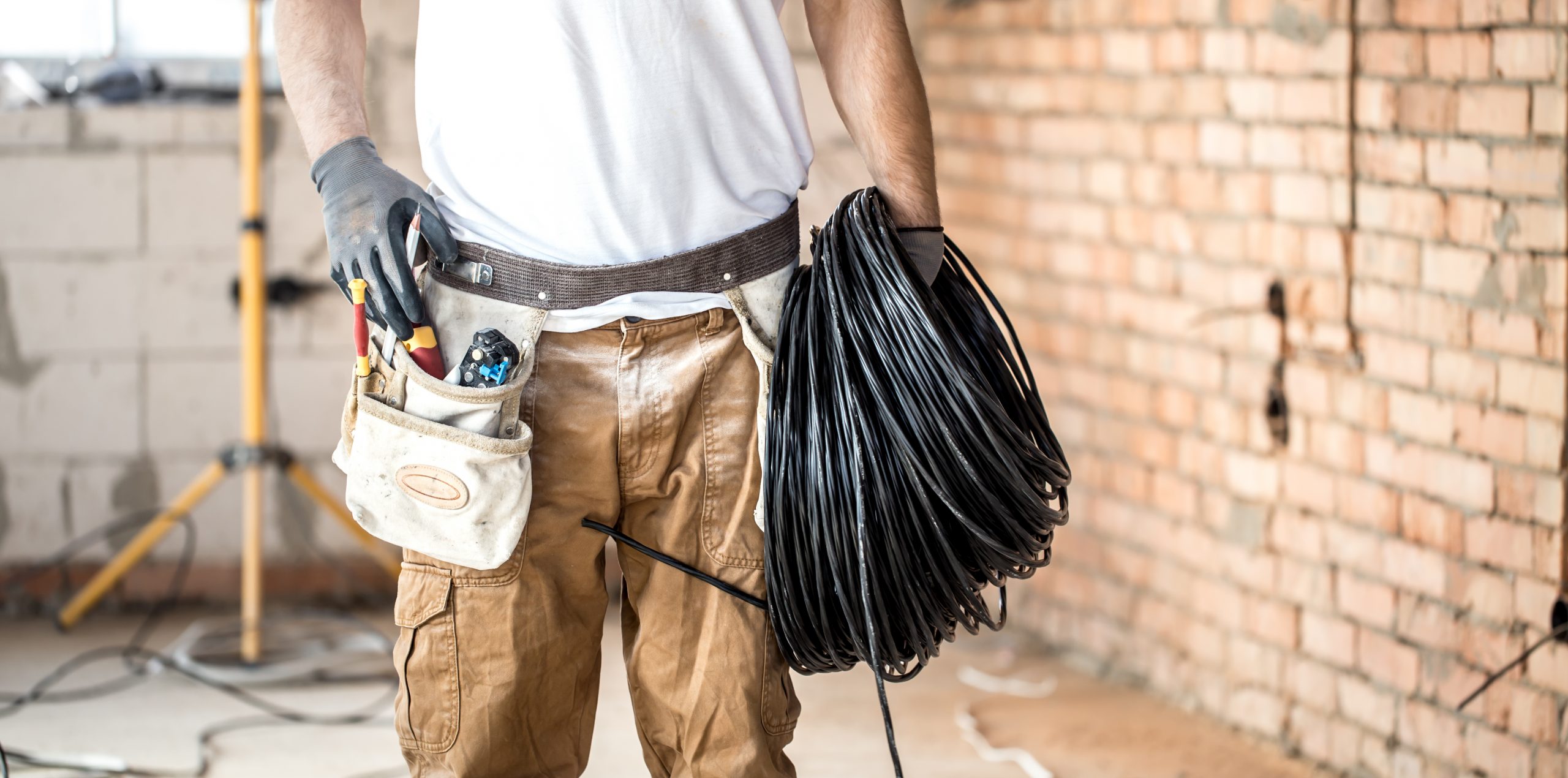 Electrician with tools, working on a construction site. Repair and handyman concept. House and house reconstruction.